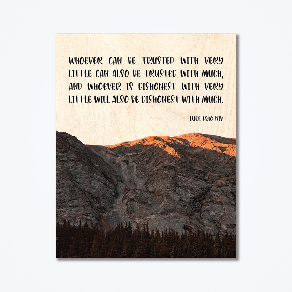 A wood poster with a mountain range and a quote about trust printed on it.