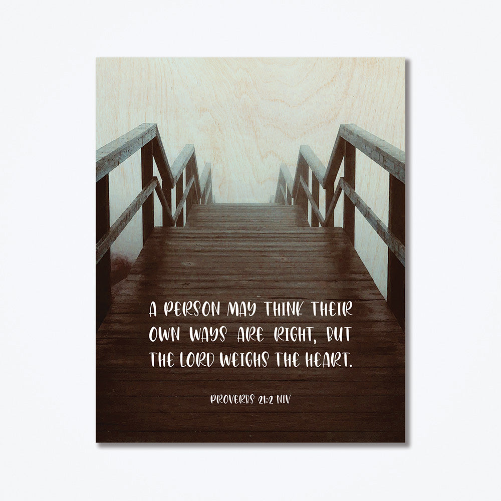 A wood poster with white bible text as well as an image of a staircase going down to the beach.